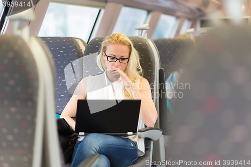 Image of Woman travelling by train working on laptop.