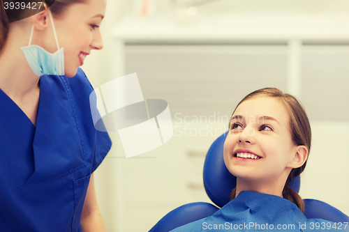 Image of happy female dentist with patient girl at clinic