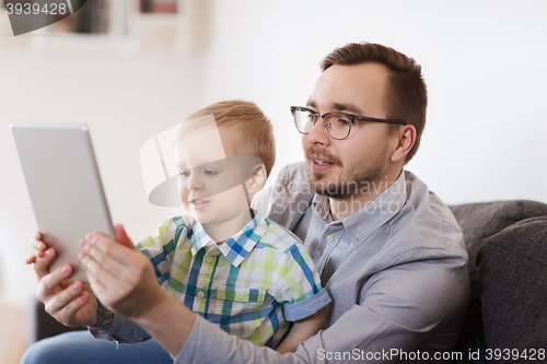 Image of father and son with tablet pc playing at home