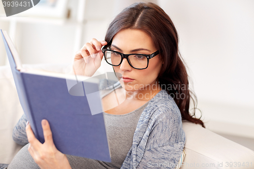 Image of pregnant woman reading book at home