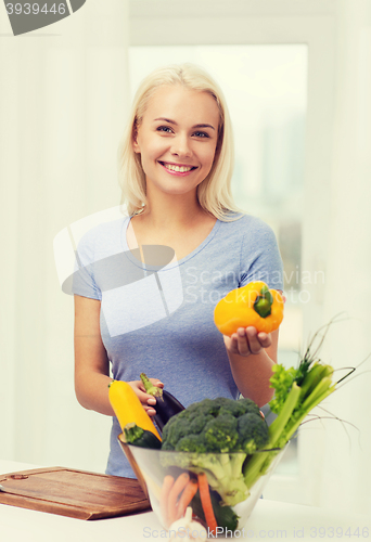 Image of smiling young woman cooking vegetables at home