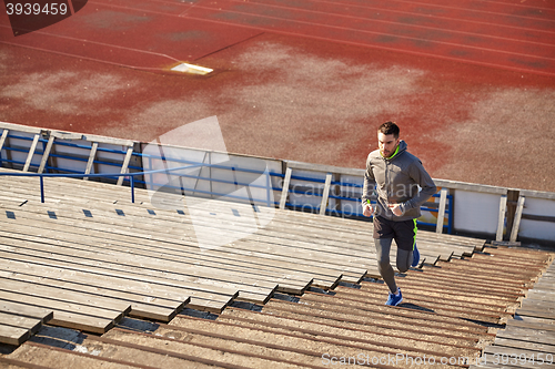 Image of happy young man running upstairs on stadium