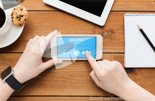 Image of close up of woman with smartphone on wooden table