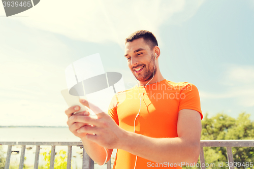 Image of smiling young man with smartphone and earphones