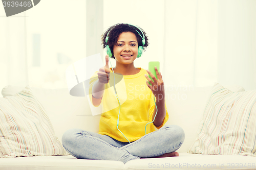 Image of happy african woman with smartphone and headphones