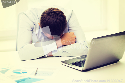 Image of businessman with laptop and papers in office