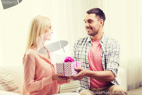 Image of happy man giving woman gift box at home