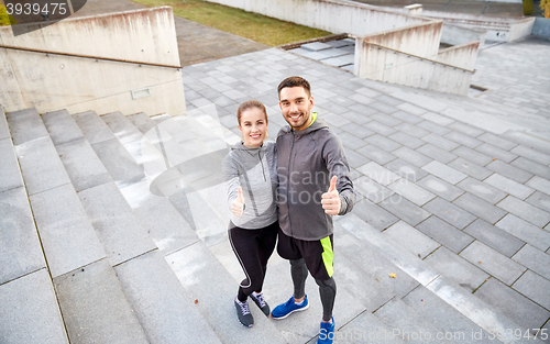 Image of smiling couple showing thumbs up on city street