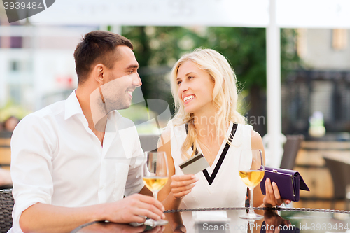 Image of happy couple with bank card and bill at restaurant