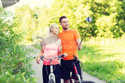 Image of couple with bicycle and smartphone selfie stick