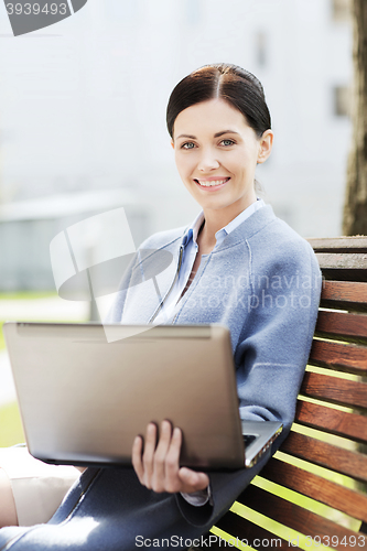 Image of smiling business woman with laptop in city