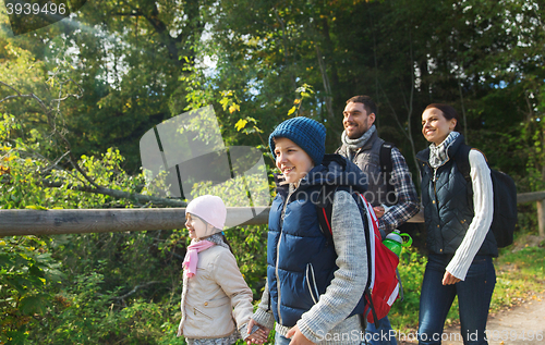 Image of happy family with backpacks hiking in woods