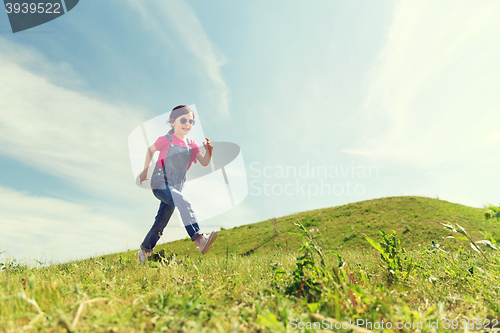 Image of happy little girl running on green summer field