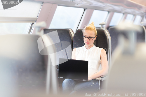 Image of Woman travelling by train working on laptop.