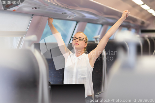 Image of Woman streching while travelling by train.