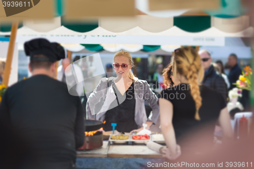 Image of Woman buying meal at street food festival.