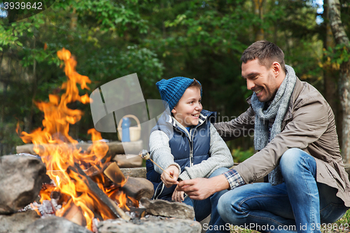 Image of father and son roasting marshmallow over campfire