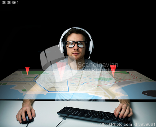 Image of man in headset with computer keyboard and gps map