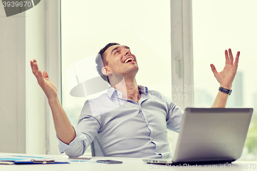 Image of happy businessman with laptop in office