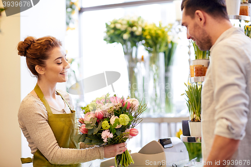 Image of smiling florist woman and man at flower shop