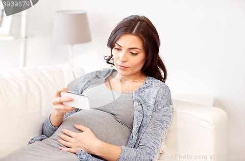 Image of sad pregnant woman with smartphone at home