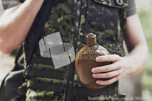 Image of close up of soldier with gun and flask in forest