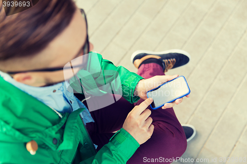 Image of close up of man with smartphone sitting on bench