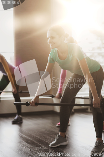 Image of group of people exercising with bars in gym