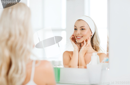 Image of woman in hairband touching her face at bathroom