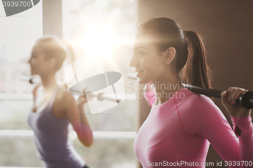 Image of group of people exercising with bars in gym