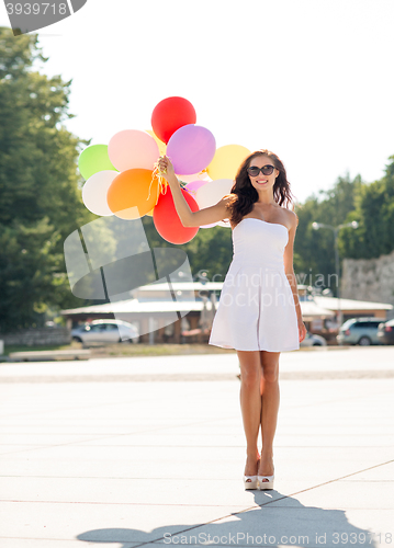 Image of smiling young woman in sunglasses with balloons