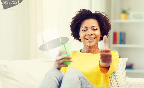 Image of happy african woman with smartphone at home