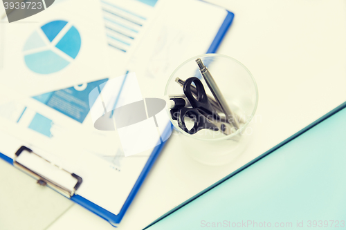 Image of close up of cup with scissors and pens at office