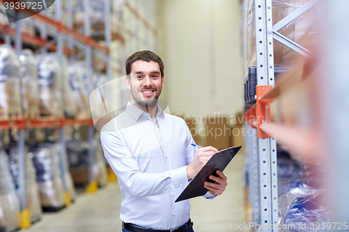 Image of happy businessman with clipboard at warehouse