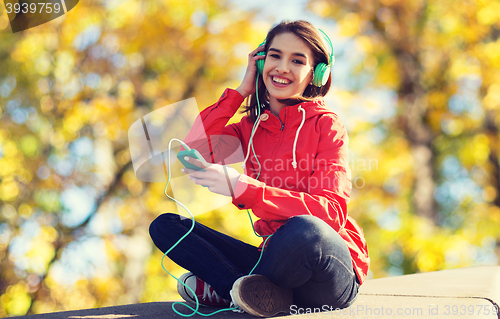 Image of happy young woman with smartphone and headphones