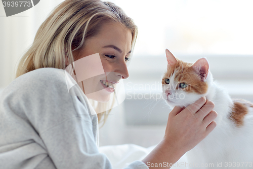 Image of happy young woman with cat in bed at home