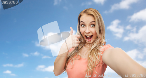 Image of happy woman taking selfie and showing thumbs up