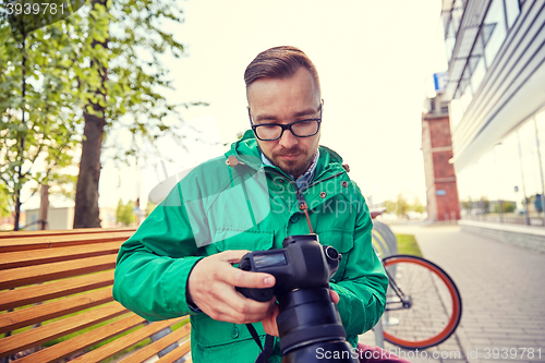 Image of young hipster man with digital camera in city