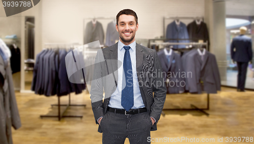 Image of happy young businessman over clothing store