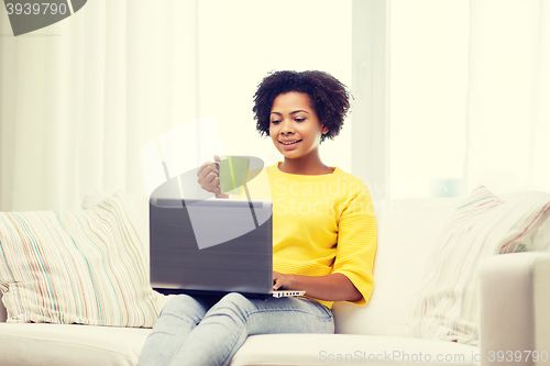 Image of happy african american woman with laptop at home