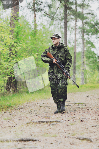 Image of young soldier or hunter with gun in forest