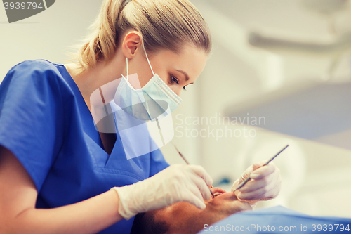 Image of female dentist checking up male patient teeth