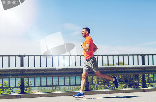 Image of smiling young man running at summer seaside