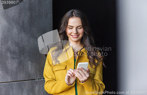 Image of smiling young woman or girl texting on smartphone