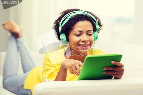 Image of happy african woman with tablet pc and headphones