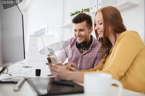 Image of happy creative team with smartphones at office