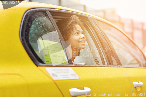 Image of happy african american woman driving in taxi