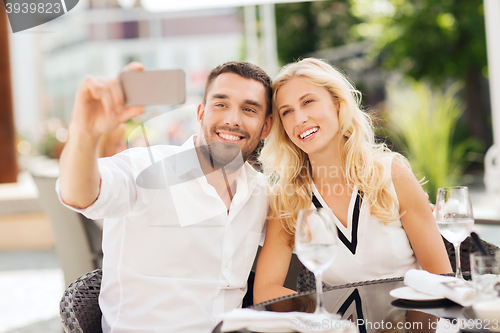 Image of happy couple taking selfie with smatphone at cafe