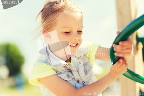 Image of happy little girl climbing on children playground