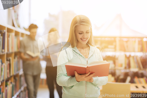 Image of happy student girl or woman with book in library